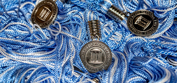 closeup of carolina blue and white graduation tassels with old well charms