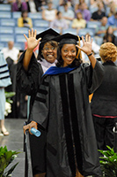 Two students waving to family at hooding ceremony