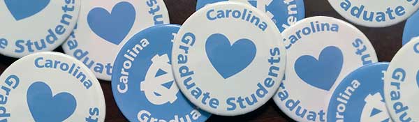 Collection of blue and white buttons saying, 'Carolina Loves Graduate Students'
